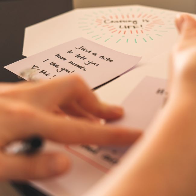 close up of hands writing love messages in a card