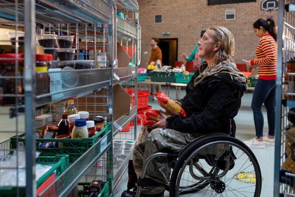 Man in wheelchair looking at a rack of food in a community food club