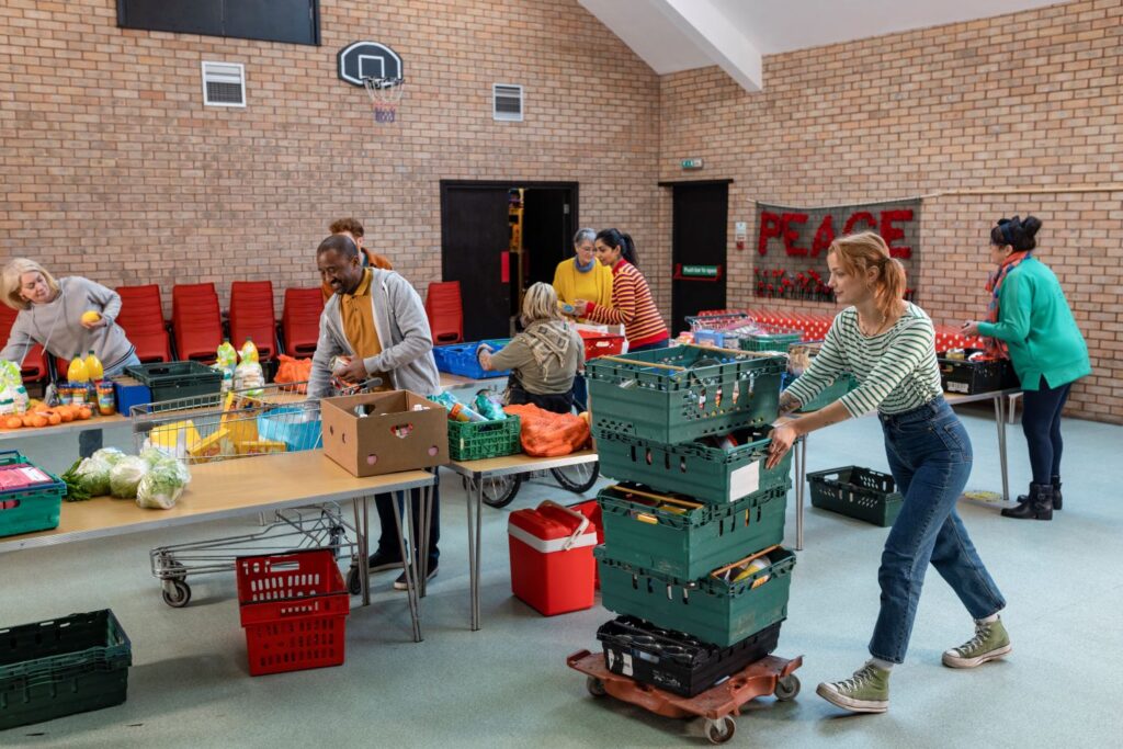 A female volunteer pushes a trolley of food crates through community centre