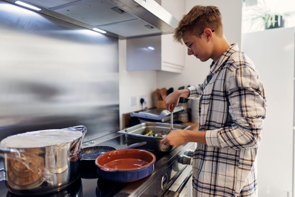 A teenage boy prepares food in commercial kitchen