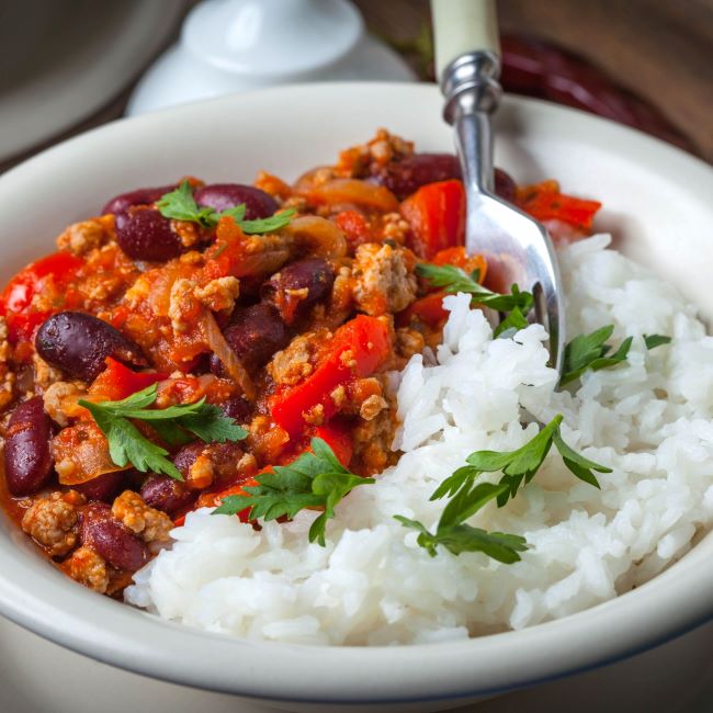 A bowl of vegetarian chilli and rice with herb garnish
