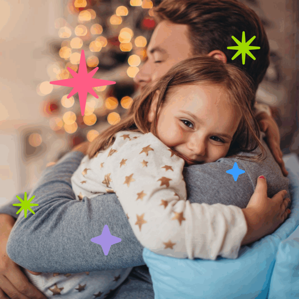 A man holding a smiling little girl in his arms in front of a glistening Christmas tree. It's Family Action's hero image for the 2025 Christmas Toy Appeal.
